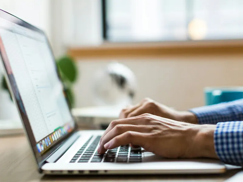 Hände tippen auf der Tastatur eines Laptops